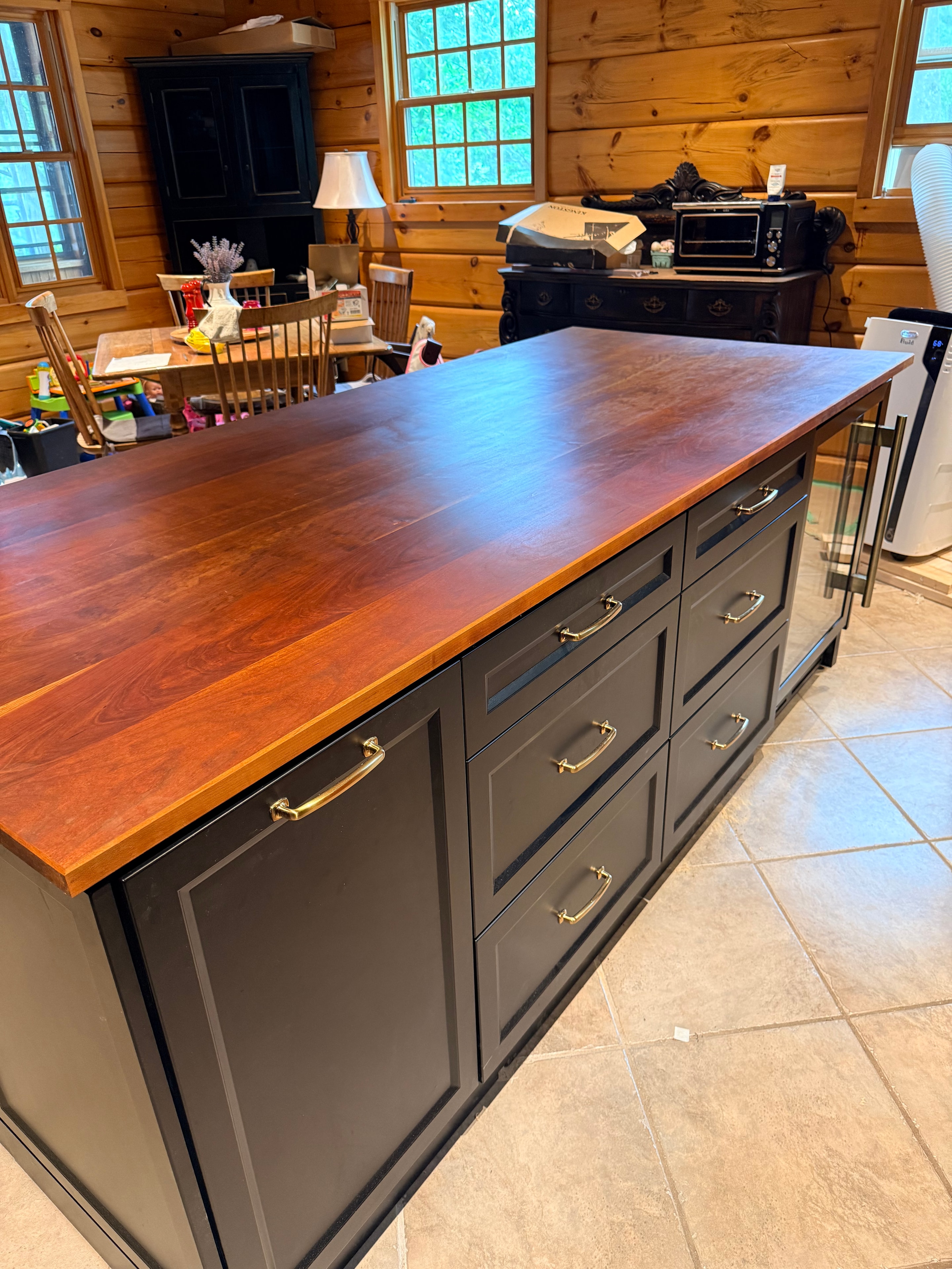 Black cabinetry with wood countertop island and brass hardware